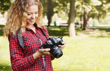 Young female student taking photos in the park with camera. Photography classes, education and...