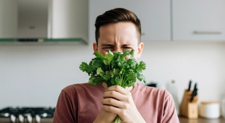 Man holding cilantro near his face in kitchen