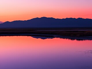 Fototapeta premium serene sunset reflection over calm waters with mountains in the background