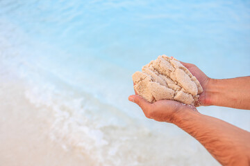 A man is holding a handful of sand on a beach