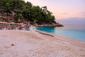 A beach with a few umbrellas and a few people sitting under them