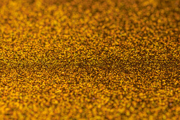 The image is a close up of a gold glittery surface