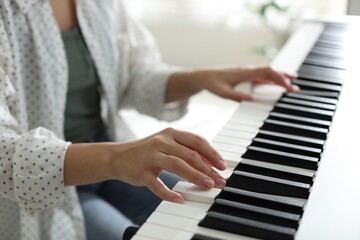 Fototapeta premium Woman playing synthesizer indoors, closeup. Electronic musical instrument