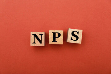 NPS (net promoter score) abbreviation made of wooden cubes on red background, top view