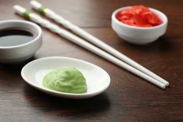 Hot wasabi paste, soy sauce, ginger and chopsticks on wooden table, closeup