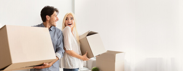 Excited Spouses Carrying Moving Boxes Smiling Looking At Each Other Leaving Old Flat. Free Space