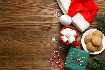 Festive Christmas composition with Santa hat, cookies and hot cocoa with marshmallows on wooden background