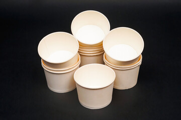 Disposable kraft paper bowls, isolated on black background. High resolution photo.