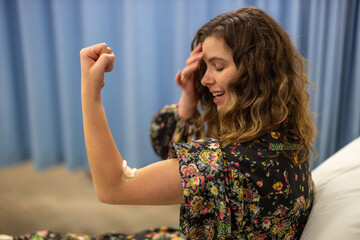 Woman in hospital smiling with strength after donating blood. Bandage on arm, accomplishment and...