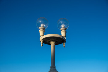 A lamppost with two round lamps against the sky.