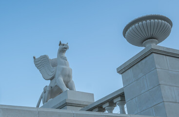 A stone griffin on a pedestal against the sky.