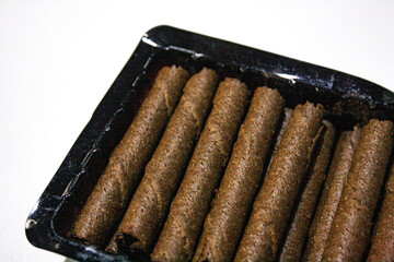 Chocolate wafer rolls in a plastic packaging on white background