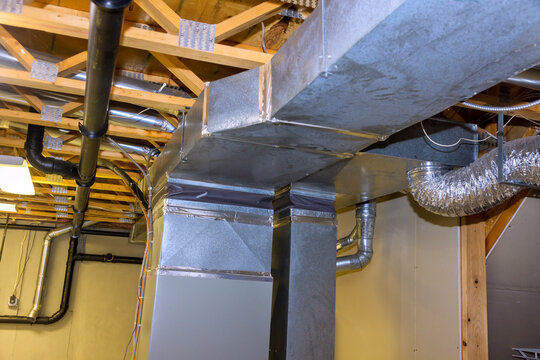 Metal ductwork is residential basement, displaying well organized HVAC system installation features various pipes, vents overhead, ensuring proper air circulation.