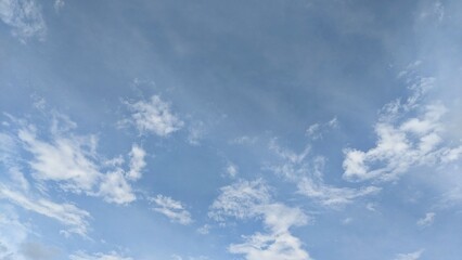 A vast expanse of blue sky dotted with fluffy white cumulus clouds. The clouds vary in size and...