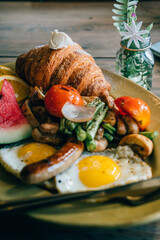 Close up of breakfast food croissant and fried egg grilled vegetables bacon