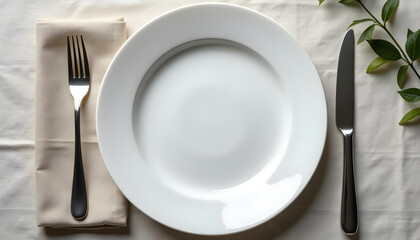 clean white plate is set on table with fork and knife, accompanied by napkin and green leaf. arrangement creates simple yet elegant dining atmosphere