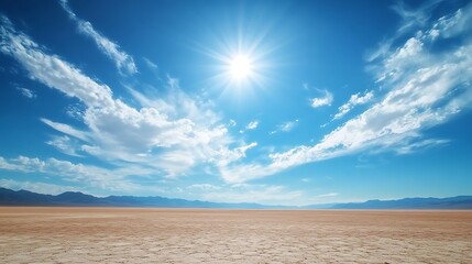 Expansive desert sky with a few scattered clouds and the sun beating down on the barren landscape