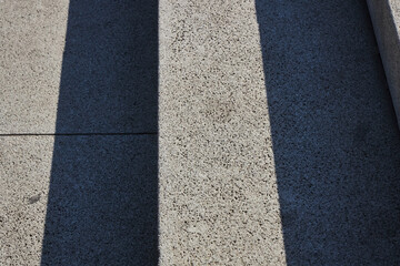 Concrete steps of a staircase made of gray blocks close up. Straight lines, hard shadows. Urban development. 