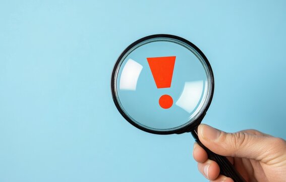 Hand Holding Magnifying Glass with Red Exclamation Mark for Attention Notification and Maintenance Alert