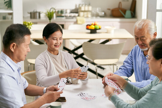 happy senior asian people playing cards at home