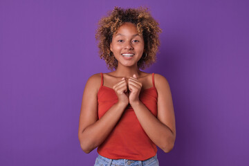 Young African American woman stands with a bright smile, showing excitement. She wears a casual red...