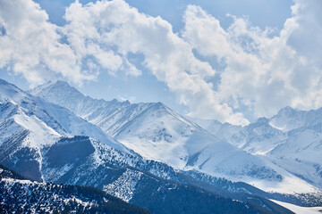 Snow capped hills, mountains. Chunkurchak valley in Kyrgyzstan. Winter natural landscape, mountain range wallpaper, panoramic view. Epic blue sky with white beautiful clouds