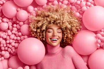 Obraz premium Joyful young woman among pink balloons indoor playful environment lifestyle portrait cheerful concept for brightening mood