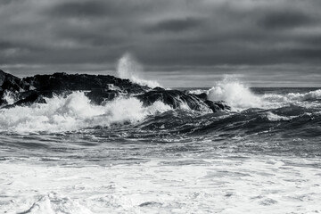 dramatic waves crashing on coastal rocks stormy clouds on sea black and white drama 