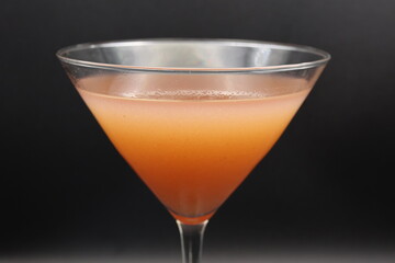 A vibrant close-up of a cosmopolitan martini in a sleek glass, garnished with a lime twist. The pink hue and elegant presentation make this cocktail a true classic.