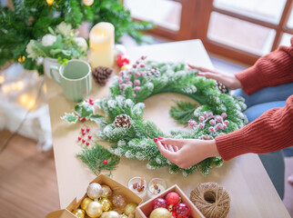 Woman making mistletoe wreath Christmas wreath decoration with hand made DIY winter greenery florist hands making Christmas wreath beautiful mistletoe.