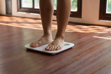 Fat diet and scale feet standing on electronic scales for weight control. Measurement instrument in...