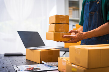 Close-up of a businessman’s hand packing items at a desk, preparing products for shipping. Highlighting delivery services for private companies online shopping with credit cards for convenience