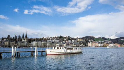 Fototapeta premium Urban landscape of Lucerne, Switzerland, viewed from the shores of Lake Lucerne on a bright and sunny spring day, showcasing the city’s charm and natural beauty.