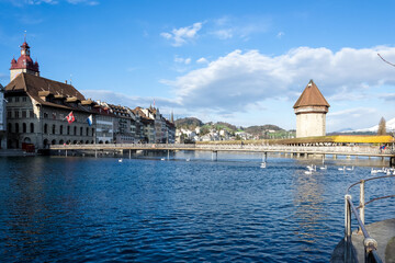 View of Lucerne’s Old Town (Altstadt) along the Reuss River, with the Kapellbrücke (Chapel Bridge), a historic covered wooden footbridge and major landmark, visible in the background.