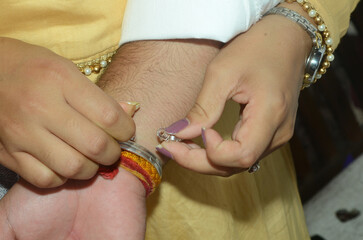 A girl tie up a silver band in her brother arms during the marriage function  1