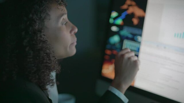A dedicated professional woman meticulously analyzing complex data presented on a computer screen