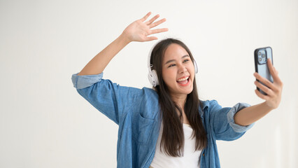 Fototapeta premium A young asian woman enjoying listening music and dancing over white background