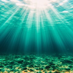 Obraz premium Underwater sunbeams illuminate ocean floor, rocks, and green water.