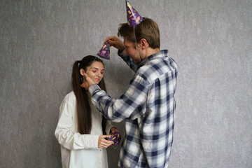 Two friends playfully adjust each other's new year festive hats while sharing laughs in a joyful...
