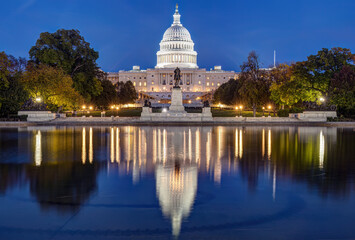 The famous illuminated United States Capitol in Washington DC at night reflected in a pond