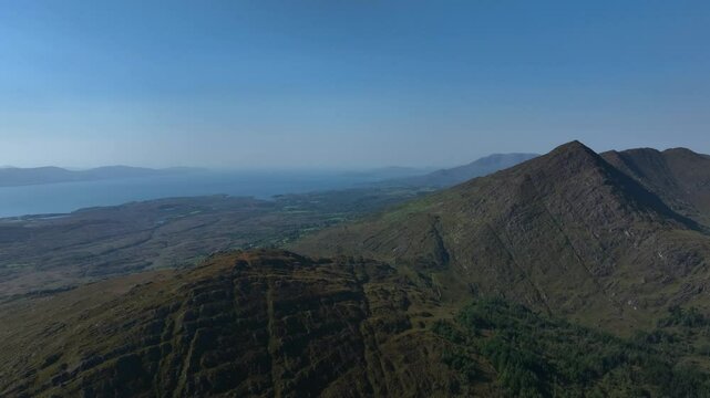 Sugarloaf, Caha Mountains, County Cork, Ireland, September 2024. Drone orbits clockwise across the stunning rugged peaks surrounded by a wild craggy landscape on the North Atlantic Ocean.