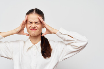 Stress, frustration, emotions, expression, young woman showing discomfort with hands on head against a light background, wearing a white shirt