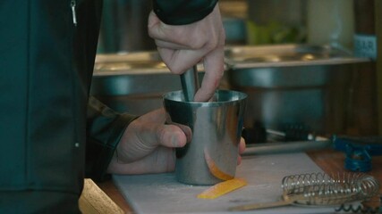 Bartender mixing ingredients with a metal mortar.