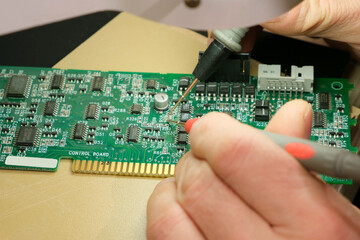 The Engineer Technician testing the printed circuit board of an electronic device under a microscope. Electronic equipment repair shop.