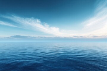Fototapeta premium A vast expanse of blue ocean water with a wispy white cloud formation in a blue sky.