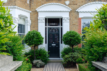 Elegant house entrance with checkered pathway and green bushes