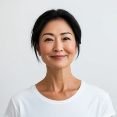 Fototapeta premium A senior Asian woman, aged 50-70, dressed in cultural attire, stands confidently against a soft gray backdrop, showcasing her timeless elegance in a studio setting.
