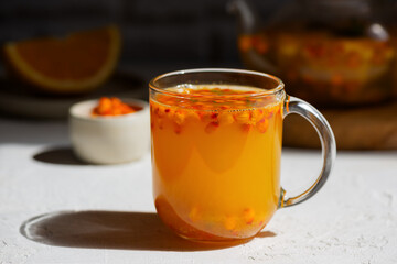 Homemade sea buckthorn autumn tea with orange, fresh berries, cinnamon, honey and herbs on white...