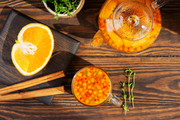 Sea buckthorn tea with orange, cinnamon, honey and thyme on wooden table. Healthy herbal autumn drink. Top view.