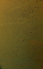 Liquid Drops On Matt Golden Surface. Vertical Stock Photo For Gold Color Background
